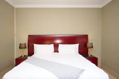 a bedroom with a large white bed with two lamps at Tamboti Guest Lodge in Pretoria