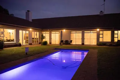 a swimming pool in front of a house at night at Amohela Guesthouse in Midrand