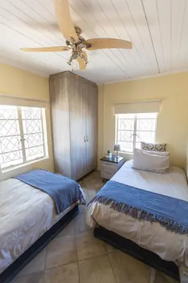 a bedroom with two beds and a ceiling fan at The Bushveld Farmhouse in Mabalingwe Nature Reserve in Warmbaths