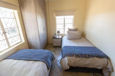 a bedroom with two beds and two windows at The Bushveld Farmhouse in Mabalingwe Nature Reserve in Warmbaths