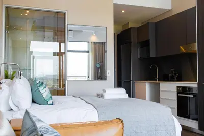 a bedroom with a large white bed and a kitchen at Menlyn Residence in Pretoria