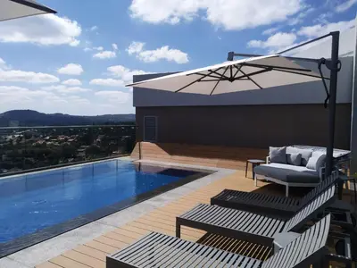 a patio with a pool and a chair and an umbrella at Menlyn Residence in Pretoria
