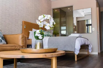 a bedroom with a bed and a table with a vase of flowers at Menlyn Residence in Pretoria