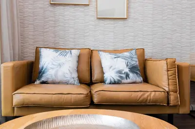a brown leather couch with two pillows on it at Menlyn Residence in Pretoria