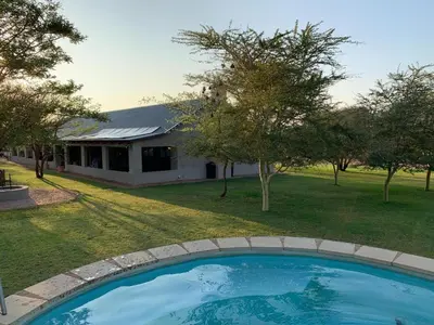 a large swimming pool in front of a house at Tula Baba Game Lodge in Brits