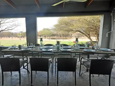 a dining room with a table and chairs and a large window at Tula Baba Game Lodge in Brits
