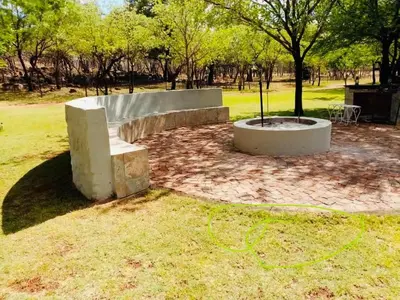a park with a bench and a tree in the grass at Tula Baba Game Lodge in Brits