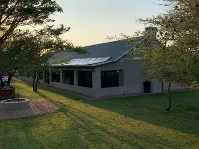 a building with a yard with trees and a building at Tula Baba Game Lodge in Brits