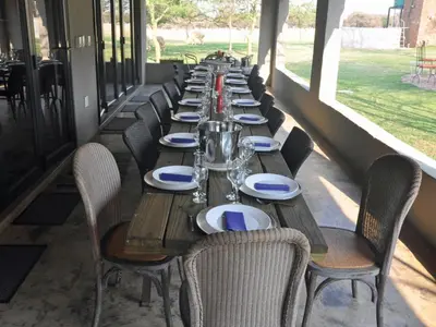 a long wooden table with chairs and plates on it at Tula Baba Game Lodge in Brits