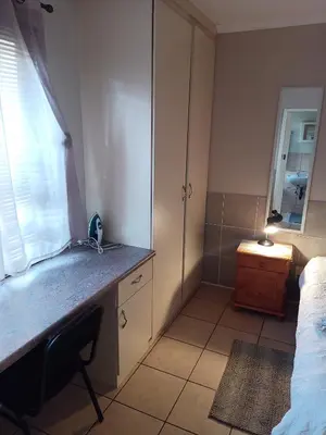 a bathroom with a sink and a desk with a mirror at Accommodation@Park1285 in Pretoria