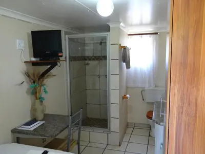 a bathroom with a shower and a television in it at Lephalale Guest House in Ellisras
