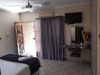 a bedroom with a bed and a desk and a television at Lephalale Guest House in Ellisras
