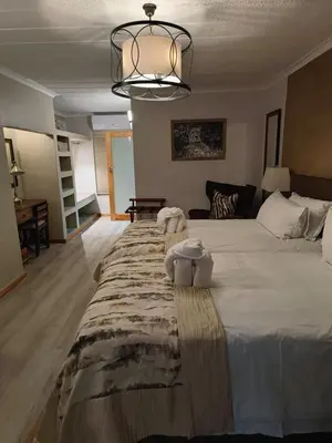 a bedroom with a large white bed with a chandelier at BushTime Mabula in Mabula