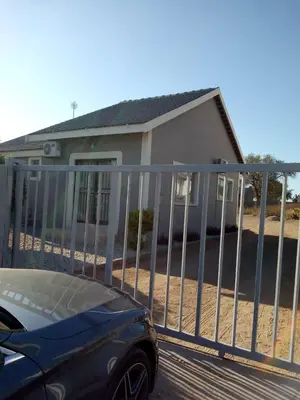 a fence in front of a house with a car at Rayon guesthouse in Phalaborwa