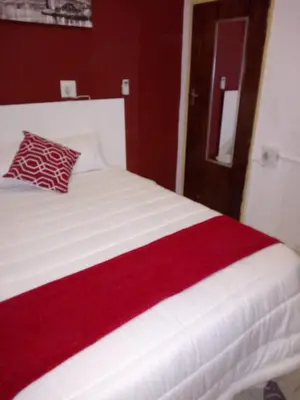 a red and white bed with a red blanket on it at Rayon guesthouse in Phalaborwa