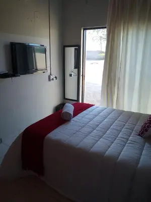 a bedroom with a bed with a television and a window at Rayon guesthouse in Phalaborwa