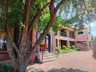 a brick building with a staircase in front of a tree at Claires of Centurion in Centurion