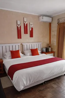 a bedroom with a large white bed with red pillows at Claires of Centurion in Centurion