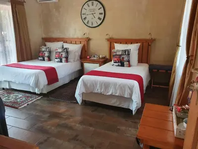 two beds in a room with a clock on the wall at Claires of Centurion in Centurion