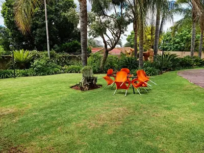 a group of chairs and a table in the grass at Casa De Jardim Guesthouse in Centurion