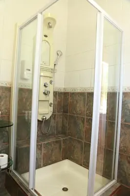 a shower with a glass enclosure in a bathroom at Casa De Jardim Guesthouse in Centurion