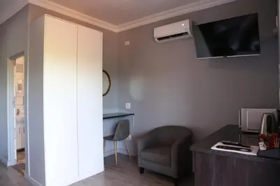 a room with a desk and a chair and a tv at Casa De Jardim Guesthouse in Centurion