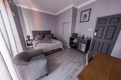 a bedroom with a bed and a chair and a table at Casa De Jardim Guesthouse in Centurion
