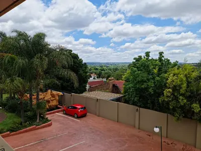 a red car parked in a parking lot next to a fence at Casa De Jardim Guesthouse in Centurion
