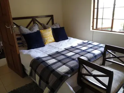 a bedroom with a bed with blue and yellow pillows at Aloha Lodge 2 Bedroom Apartment near Menlyn Sleeps 4 in Pretoria