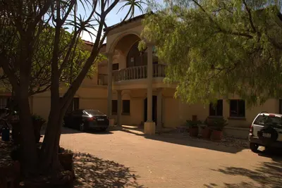 a large building with cars parked in front of it at Aloha Lodge 2 Bedroom Apartment near Menlyn Sleeps 4 in Pretoria