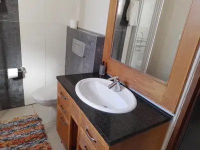 a bathroom with a sink and a mirror and a toilet at Aloha Lodge 2 Bedroom Apartment near Menlyn Sleeps 4 in Pretoria