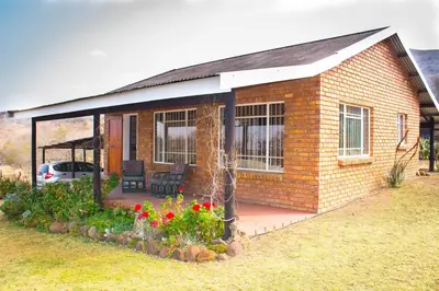 a small brick house with a patio and flowers at Stone Circle Cottage in Lydenburg