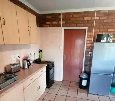 a kitchen with a refrigerator and a stove at Stone Circle Cottage in Lydenburg