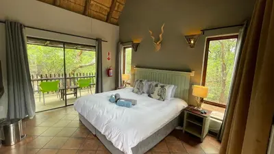a bedroom with a large bed and a balcony at Ujabule Lodge in Hoedspruit