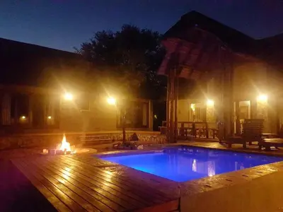 a swimming pool at night with a fire place at Ujabule Lodge in Hoedspruit