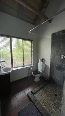 a bathroom with a toilet and a glass shower at Ujabule Lodge in Hoedspruit