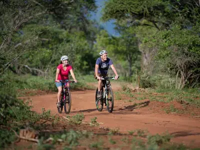 two people riding bikes on a dirt road at Ujabule Lodge in Hoedspruit