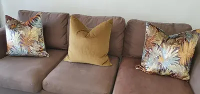 a brown couch with three pillows on it at Lush Living The Blyde Riverwalk Estate Unit 101 in Pretoria