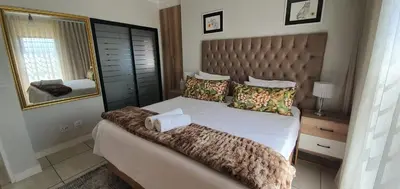 a bedroom with a large bed and a mirror at Lush Living The Blyde Riverwalk Estate Unit 101 in Pretoria