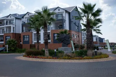 a building with palm trees in front of it at Lush Living The Blyde Riverwalk Estate Unit 101 in Pretoria