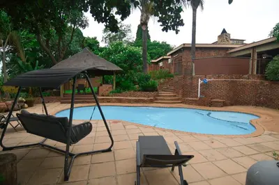 a chair and an umbrella next to a swimming pool at Upmarket Villa with pool & lush garden in Pretoria