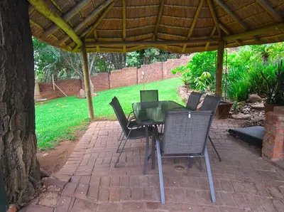 a patio with a table and chairs under a pavilion at Upmarket Villa with pool & lush garden in Pretoria