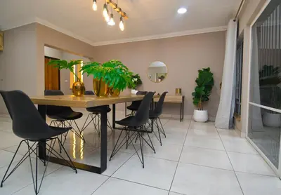 a dining room with a table and chairs at Upmarket Villa with pool & lush garden in Pretoria
