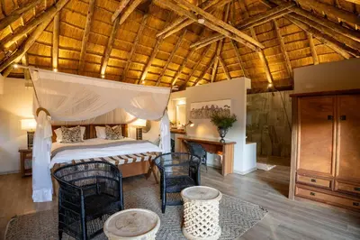 a bedroom with a bed and chairs in a room at Karongwe - River Safari Lodge in Hoedspruit