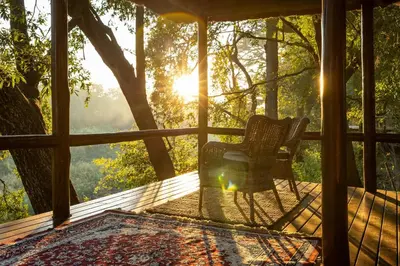 a screened in porch with a chair and the sun at Karongwe - River Safari Lodge in Hoedspruit