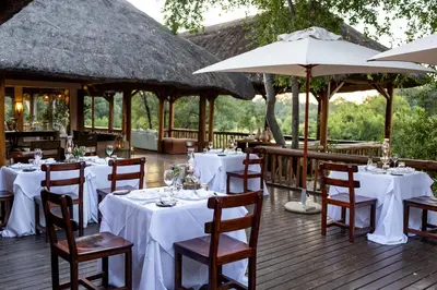 a restaurant with white tables and chairs and umbrellas at Karongwe - River Safari Lodge in Hoedspruit