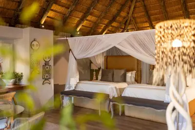 a bedroom with two beds and a canopy bed at Karongwe - River Safari Lodge in Hoedspruit
