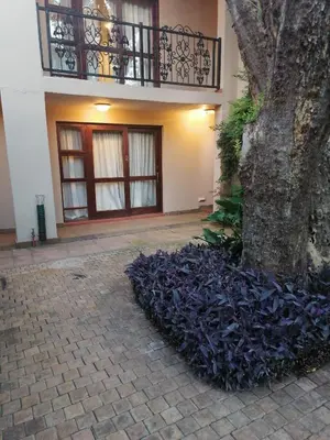 a pile of purple plants next to a tree at 180 On Anderson Guest House in Pretoria