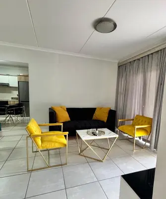 a living room with a black couch and yellow chairs at The Blyde 104 in Pretoria