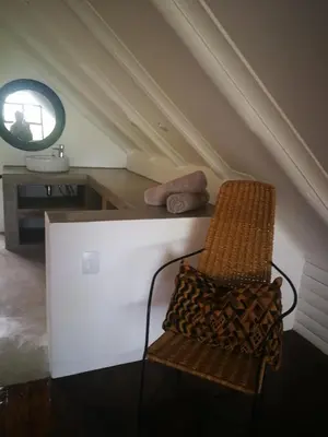 a chair in a room with a table and a mirror at Kruger River Villas- Treetop Loft in Marloth Park